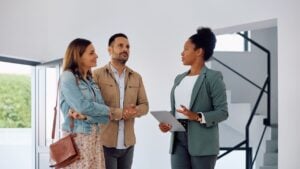 African American real estate agent communicating with potential couple of buyers during open house day.