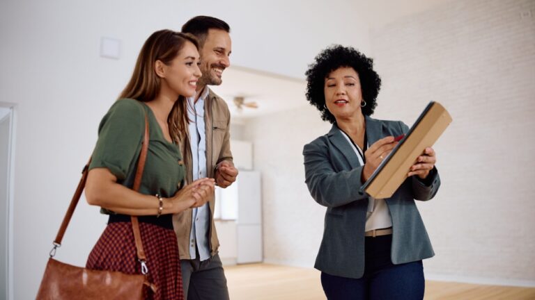 Real estate agent and young couple analyzing paperwork of a new apartment.