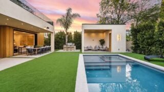 Modern backyard with a swimming pool, outdoor seating, and lush landscaping at sunset.