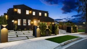 Modern luxury house exterior with well-lit facade and contemporary landscaping at dusk.