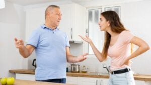 Emotional adult daughter arguing with her mature father in the kitchen