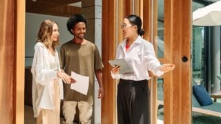 Young happy couple and an agent in a new property