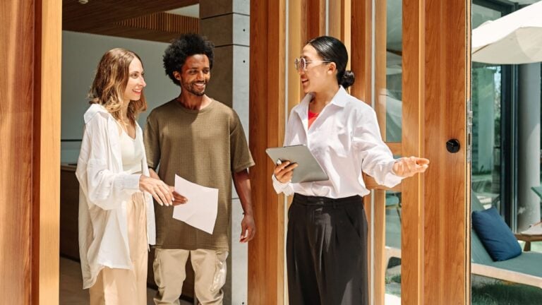 Young happy couple and an agent in a new property
