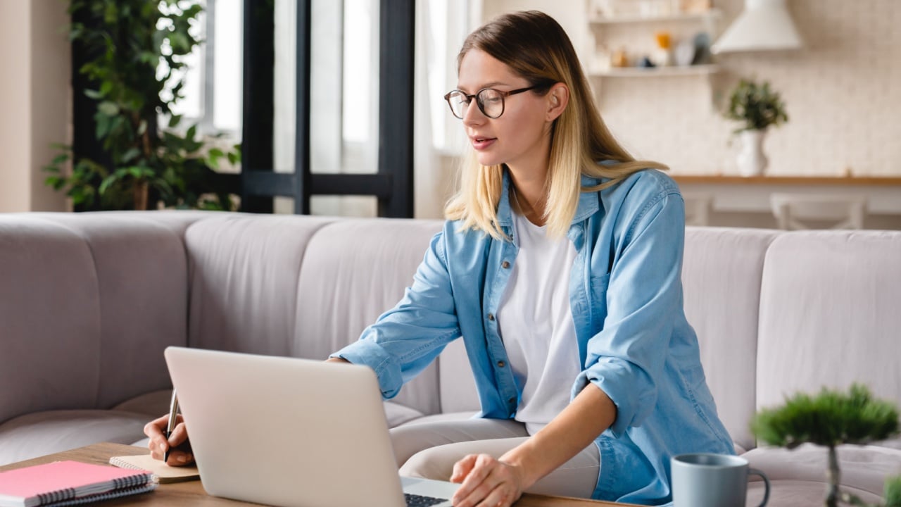 Young caucasian successful woman working remotely on distance at home using laptop on freelance. Home office.