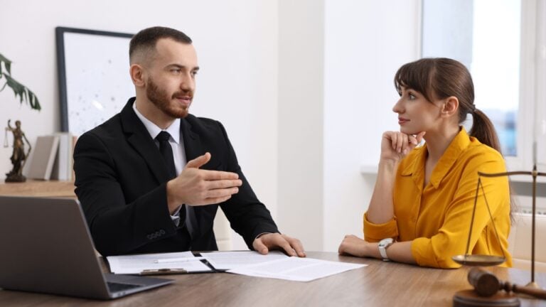Woman having meeting with professional lawyer at wooden desk indoors