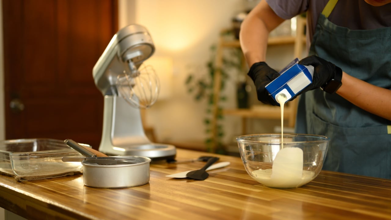 Man pouring heavy cream into glass bowl to start homemade compound butter process