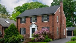 Beautiful two-story brick Colonial Revival house with black shutters and flowering bushes in Boston, Massachusetts, USA