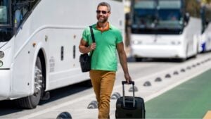 Man 40s tourist on summer vacation. Traveler trip luggage. Summer tour. Traveler enjoy summer trip. Hispanic tourist traveler walking on street. Tourist with suitcase in tropical city