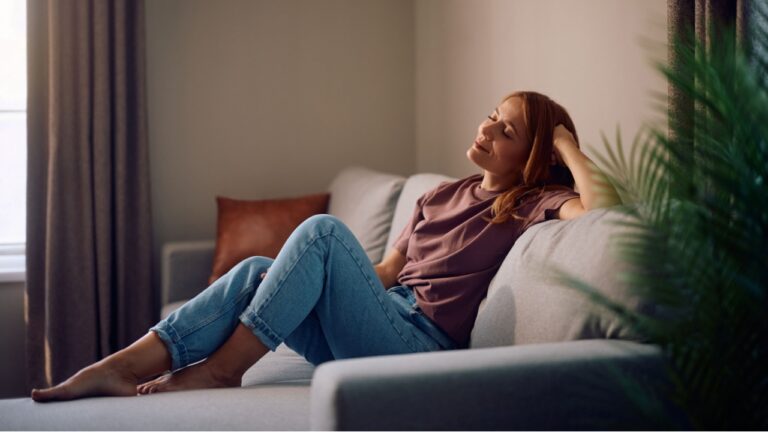 Smiling woman enjoying a day at home while relaxing on a couch with her eyes closed.