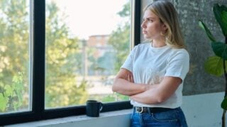 Sad unhappy young woman looking out the window, profile view.
