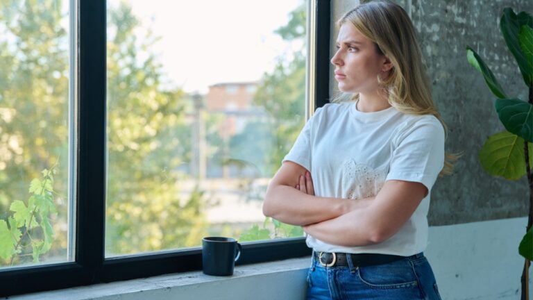 Sad unhappy young woman looking out the window, profile view.