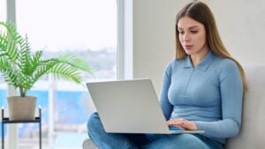 Young woman sitting on chair at home using laptop