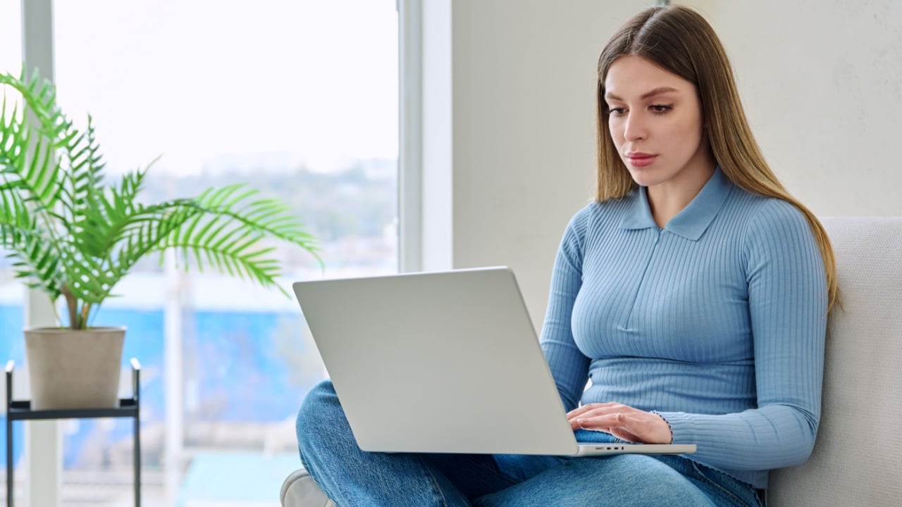Young woman sitting on chair at home using laptop