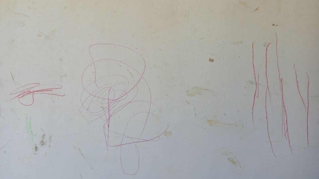 Childs Red Crayon Scribbles on Dirty White Wall