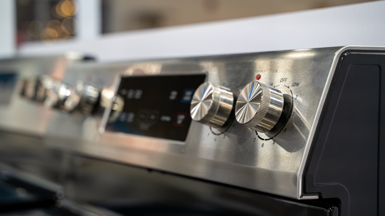 Close up of stainless steel stove control knobs and panel.