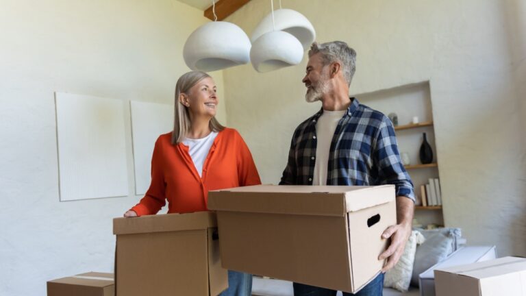 Mature couple standing with cartons during relocation