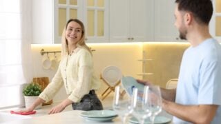 Man wiping plate while woman cleaning countertop indoors