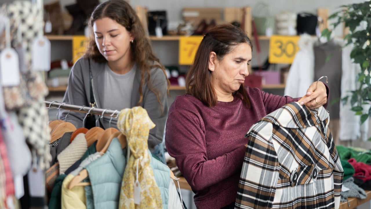 Adult and young female shoppers buying clothes for winter in clothing store