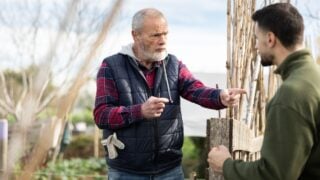 Man quarrels with mature male neighbor in suburban area garden. Ill-wishers, complaints and outrages from neighbors, shout outrages or claims