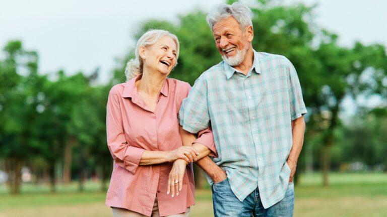 Happy active senior couple walking and holding hands outdoors