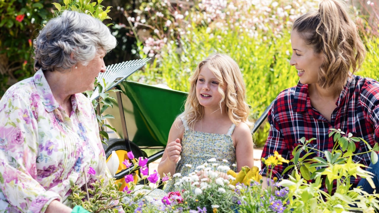 Grandmother, mother and daughter gardening together in garden