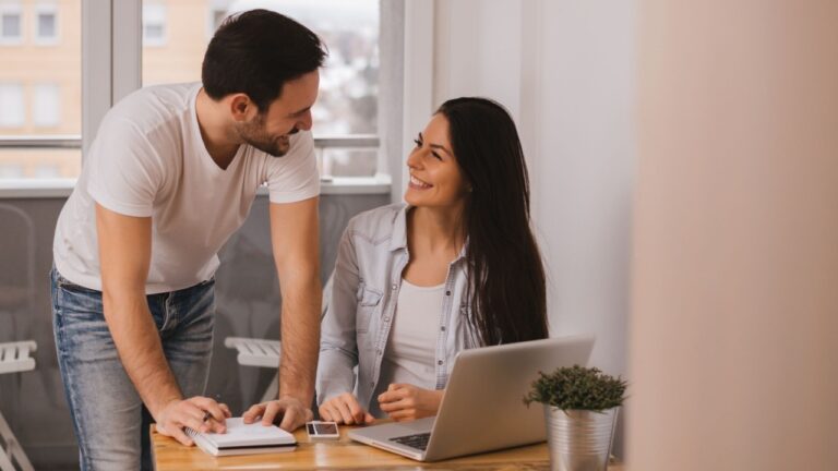 Couple working together at home, looking at each other and smiling