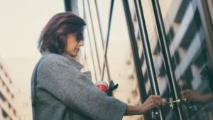 Beautiful woman unlocking door with a key and entering in residential building.