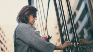 Beautiful woman unlocking door with a key and entering in residential building.
