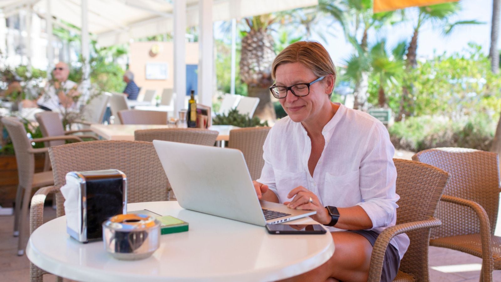 Woman sitting in a coffee bar working on her laptop. She is looking down on the screen