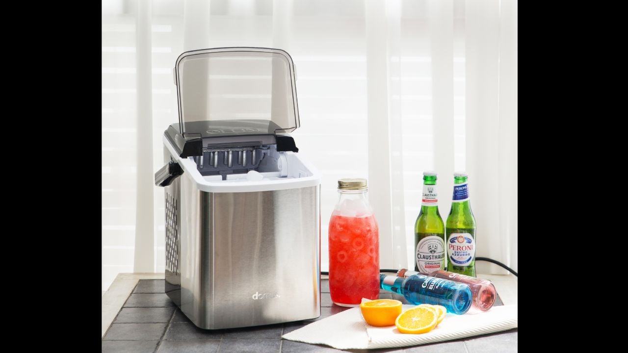 A modern stainless steel ice maker machine placed with fresh drinks, citrus fruits, and bottled beverages, perfect for home parties and summer refreshment. (04,22 2022 in Ilsan, Korea)