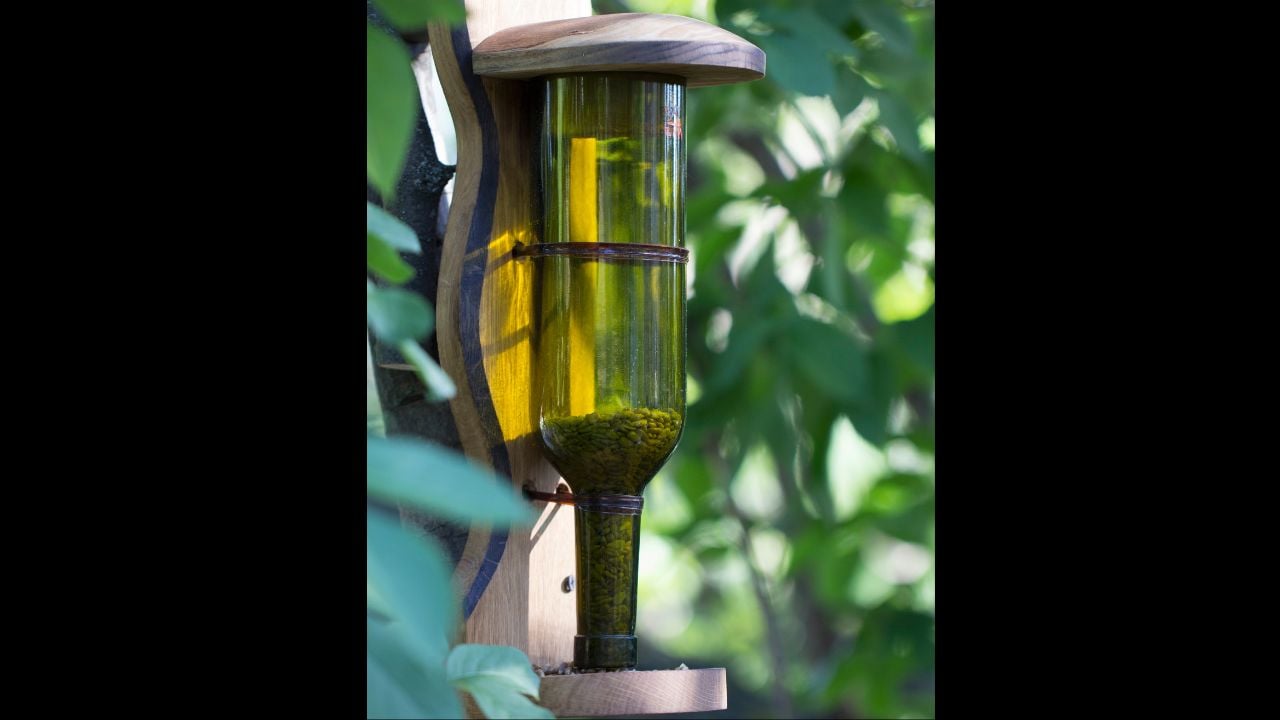 Feeder for birds, made from an empty glass flask. Use of household rubbish in decorative, and practical purposes in gardening