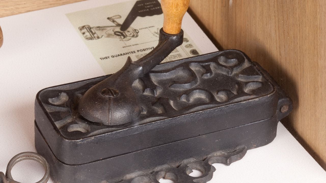 Parallelepiped wall-mounted can opener with Liberty-style racemes decoration on the upper face and equipped with a handle with a handle in light turned wood