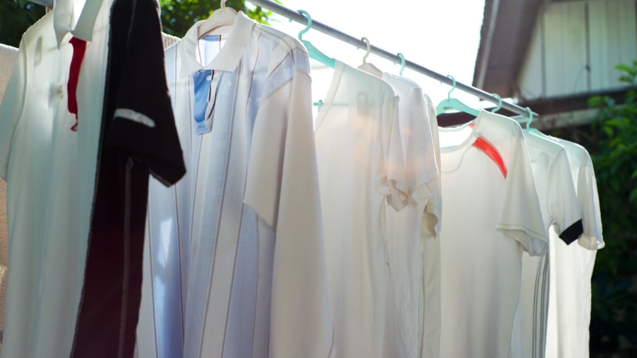 Wet clothes hanging on the steel bar for drying by the heat of sunlight. Traditional laundry drying by the sun.