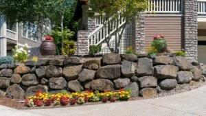House front yard garden landscaping with cut rocks retaining wall stone works facade with potted plants and flowers