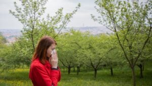 Young allergic woman blowing nose