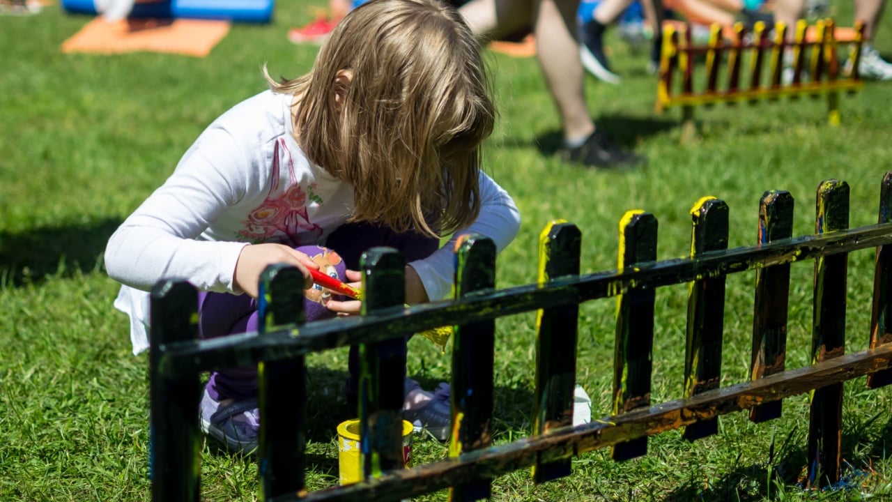 a child is painting a small fence