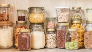 Shelf in the kitchen with various cereals and seeds - peas split, sunflower and pumpkin seeds, beans, rice, pasta, oatmeal, couscous, lentils, bulgur in glass jars