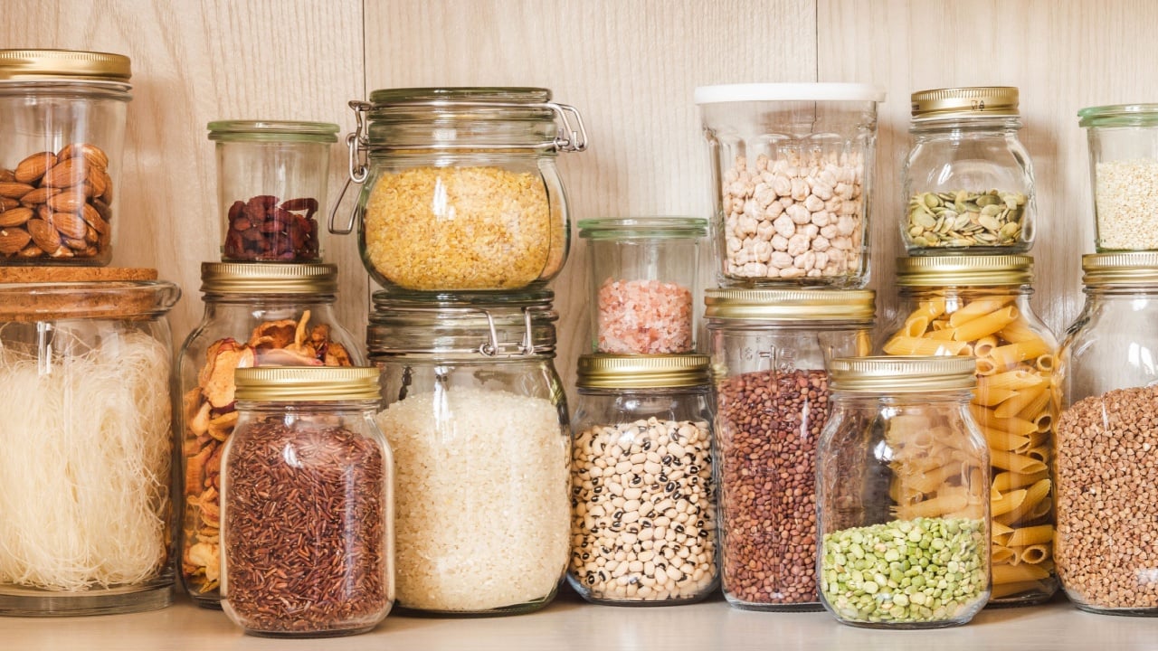 Shelf in the kitchen with various cereals and seeds - peas split, sunflower and pumpkin seeds, beans, rice, pasta, oatmeal, couscous, lentils, bulgur in glass jars
