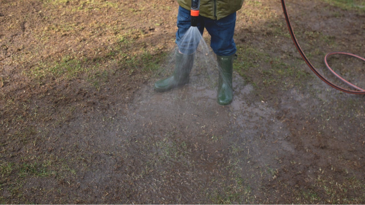 A boy is watering a spring garden from a hose.