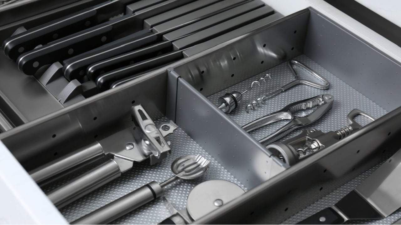 Open drawer with stainless steel utensil set, closeup. Order in kitchen
