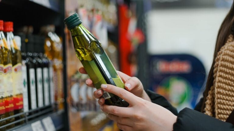 Female hand choosing natural olive oil at store. Concept of healthy food, bio, vegetarian, diet.