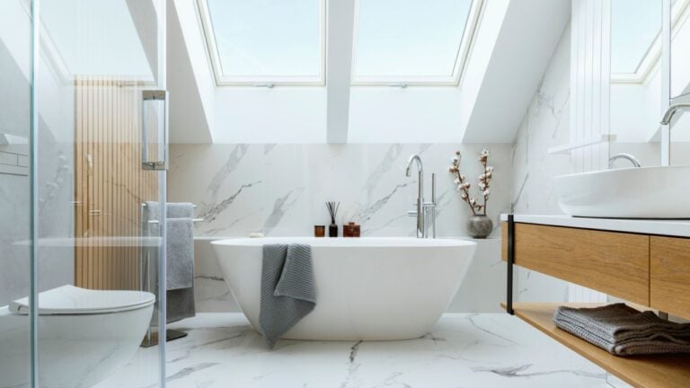 Stylish bathroom interior design with marble panels. Bathtub, towels and other personal bathroom accessories. Modern glamour interior concept. Roof window. Template.