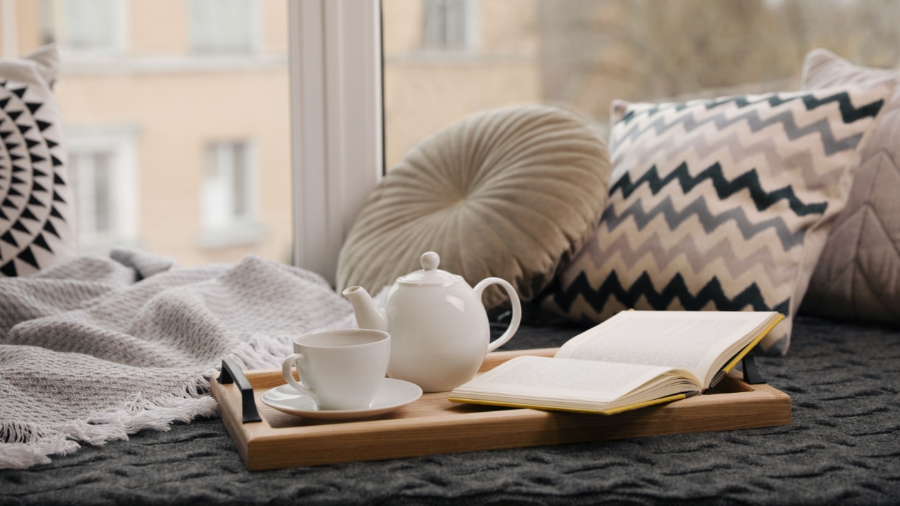 Comfortable lounge area with blanket and soft pillows near window in room