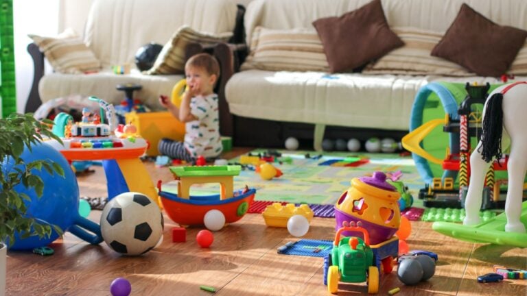 Adorable toddlers playing among the many toys at home. A mess in the children's room, a lot of toys in the children's room. Dirty house. Children's room
