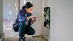 Female technician with screwdriver and terminal strip installing telecommunication box