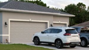 Car parked in front of wide garage double door on concrete driveway of new modern american house