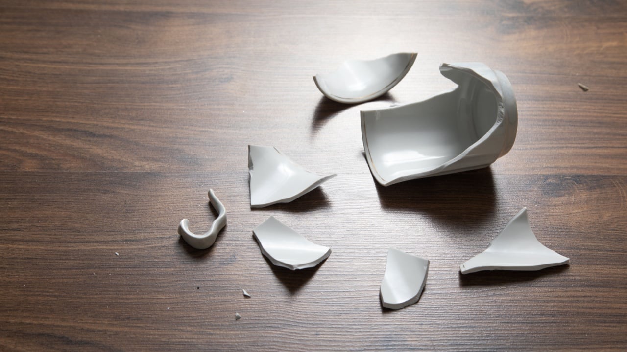 White broken cup on the wooden background.
