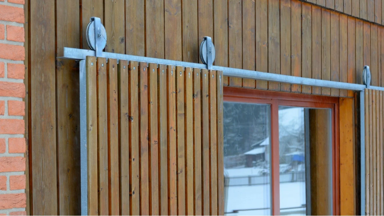 doors or barn doors made of planks that can be pulled to the side along a skid rail. the door hangs on a hinge with wheels. retractable shutters made of wood on the cottage, retractable, frame