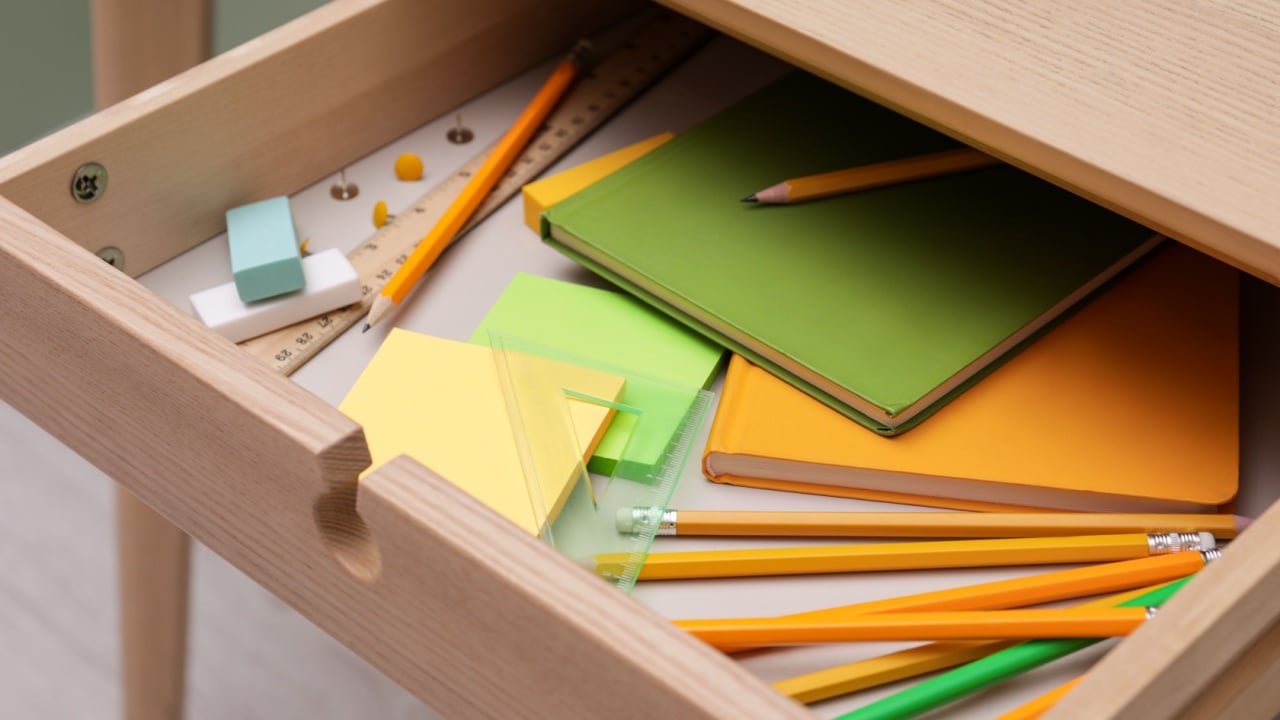 Office supplies in open desk drawer indoors, closeup