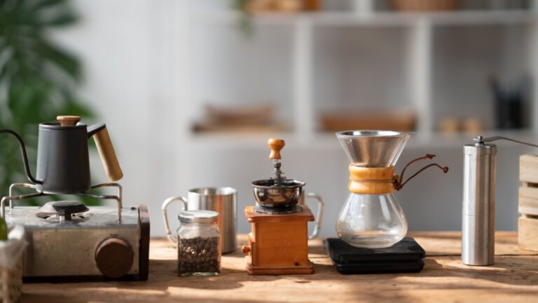 Coffee making concept, Old coffee grinder, manual hand mill on the table with coffee pot and coffee cup.